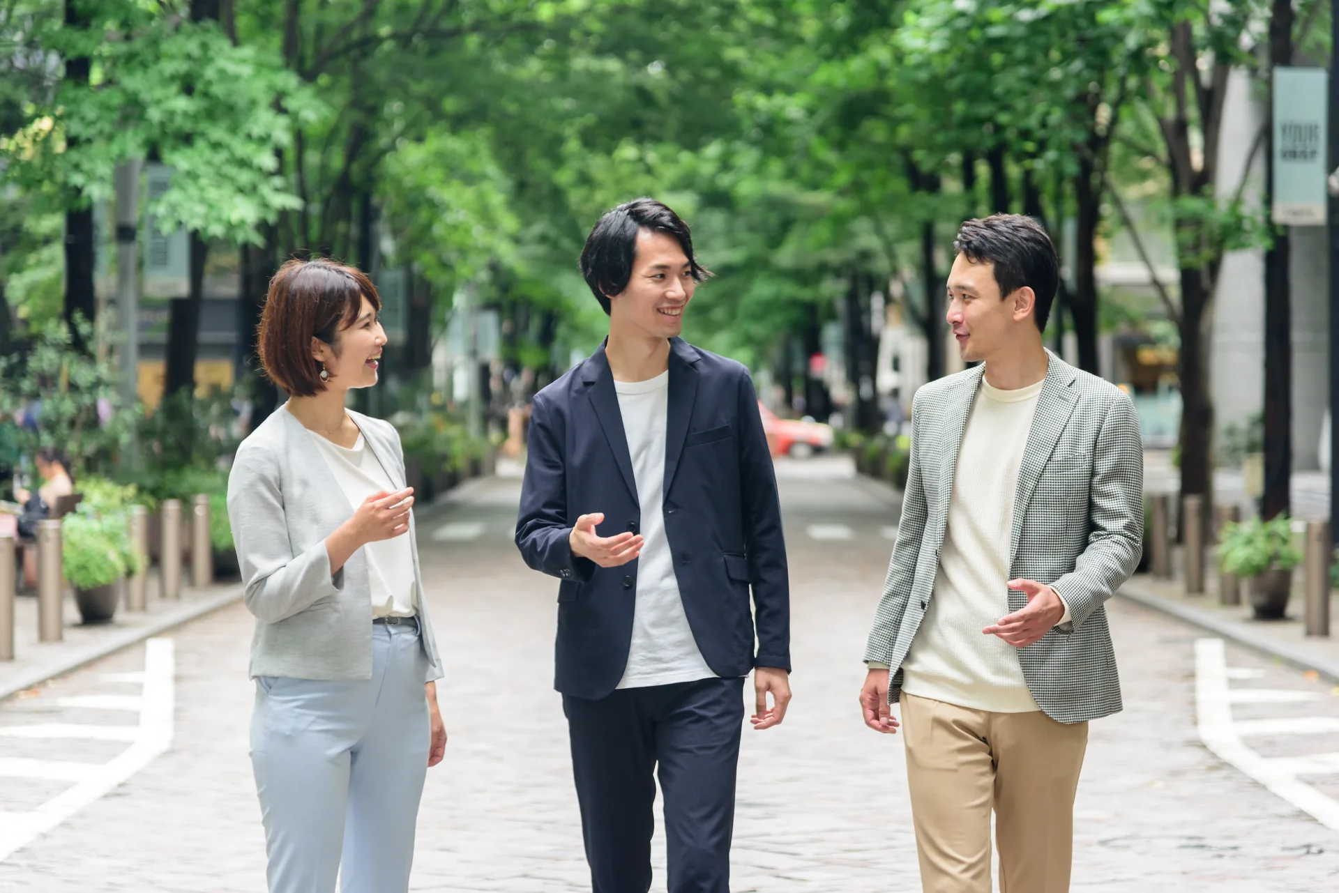 並木道を歩きながら語り合うビジネスパーソン